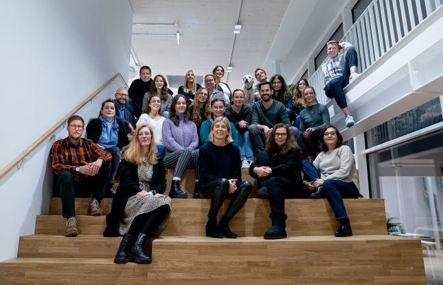 Das Team von ottomisu sitzt auf einer Treppe und alle lächeln frontal in die Kamera.