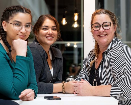 Unsere Kolleginnen aus dem Backoffice Nadja, Melodi und Kamila lächeln in die Kamera.