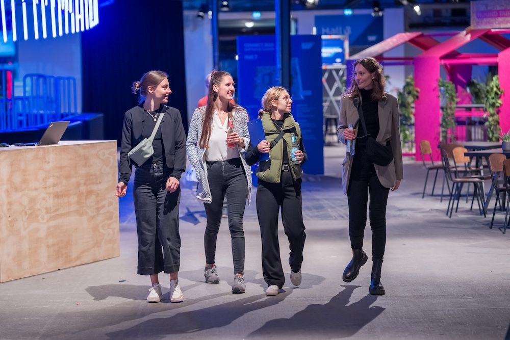 Vier Frauen mit Getränken in der Hand laufen