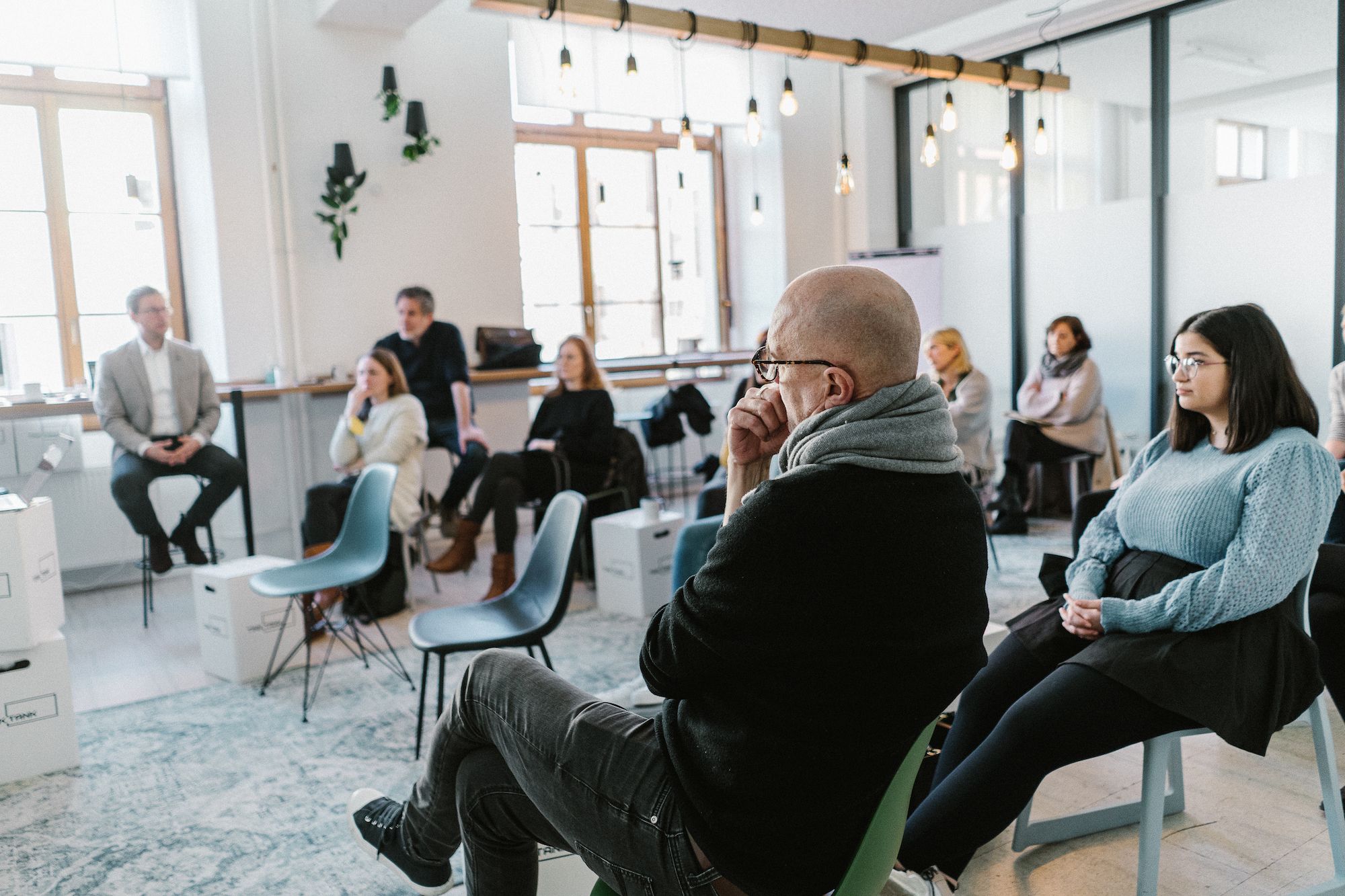 Teamfoto, auf dem das ottomisu Team in einem Raum sitzt und gemeinsam einem Vortrag lauscht