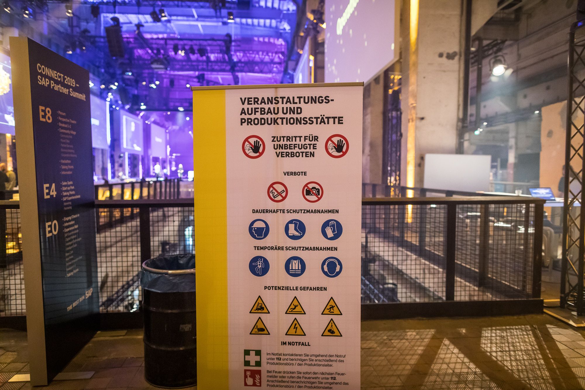 Aufbau in einer Location mit einem Aufsteller zu Sicherheitshinweisen "Veranstaltungsaufbau und Produktionsstätte"