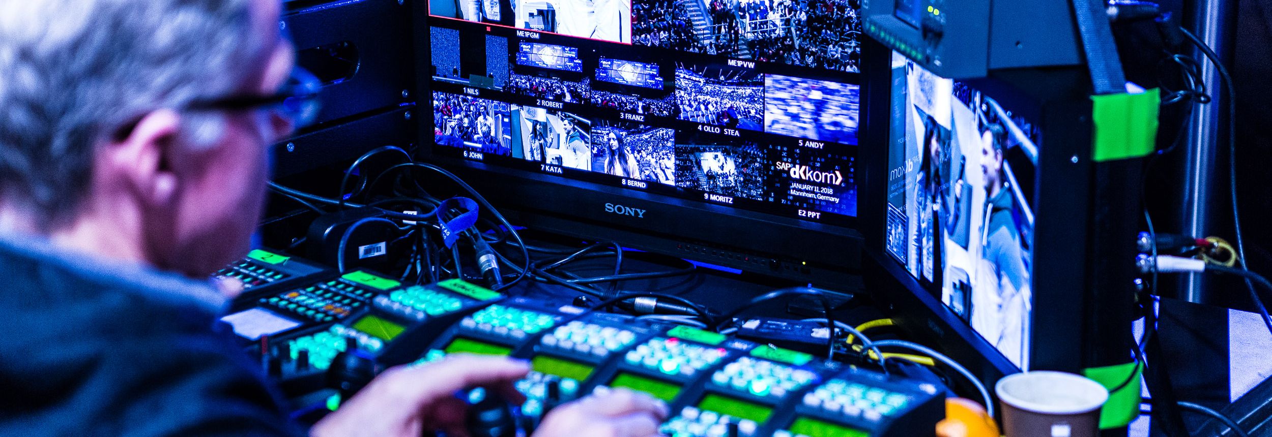 Regieplatz mit Mischpult und Monitoren bei einer Eventproduktion, zahlreiche Kamerabilder im Live-Schnitt.