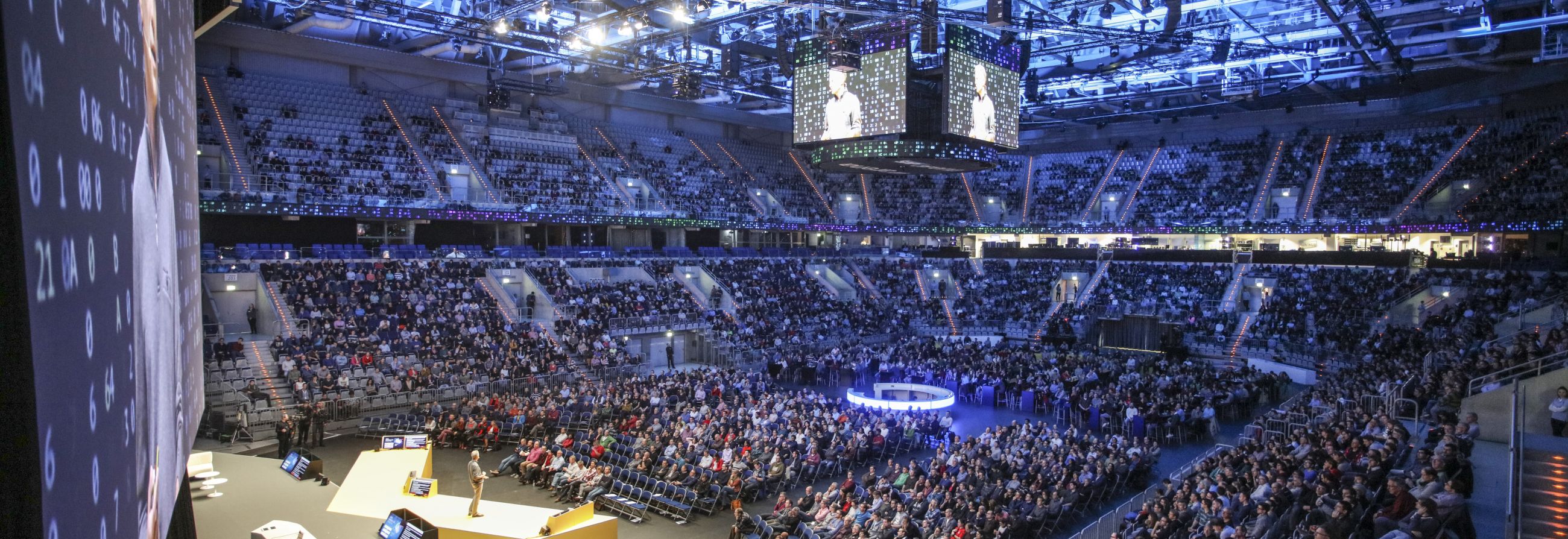 Großes Event in moderner Arena mit vollbesetztem Publikum und zentraler Bühne.