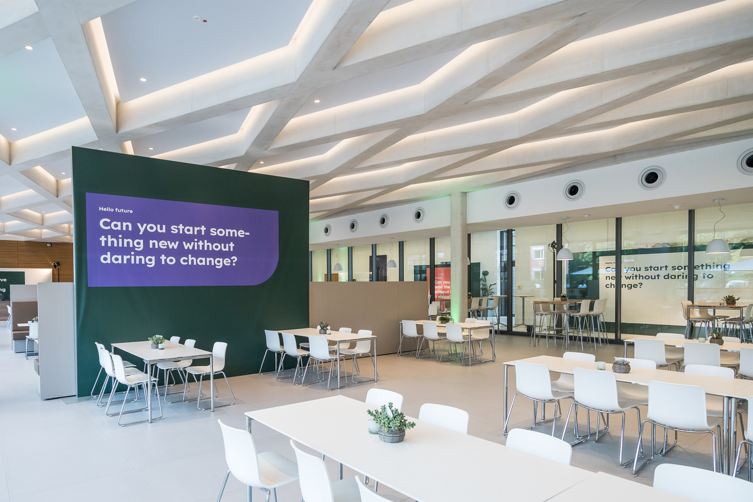 Moderner, heller Meetingbereich mit einer violett leuchtenden LED-Wand. Weiße Tische und Stühle sind gruppiert angeordnet