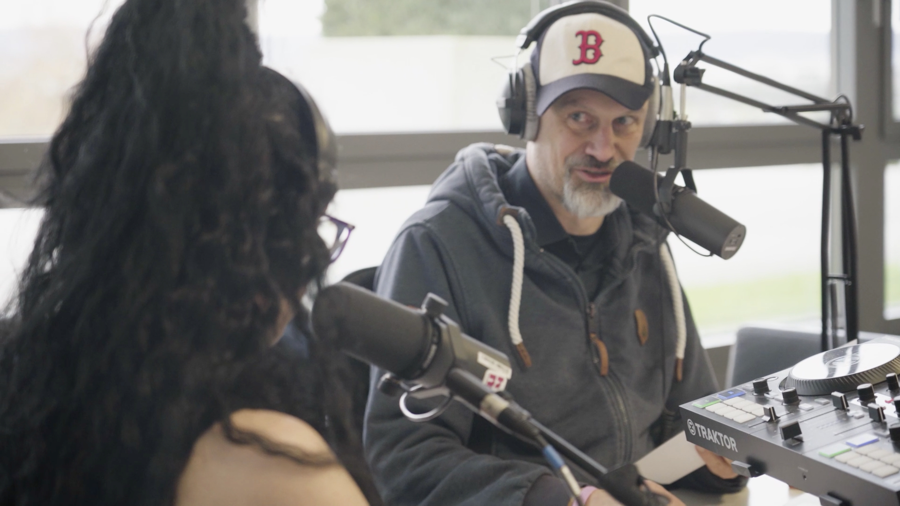 Zwei Moderatoren im Radiostudio mit Headsets und Mikrofonen.