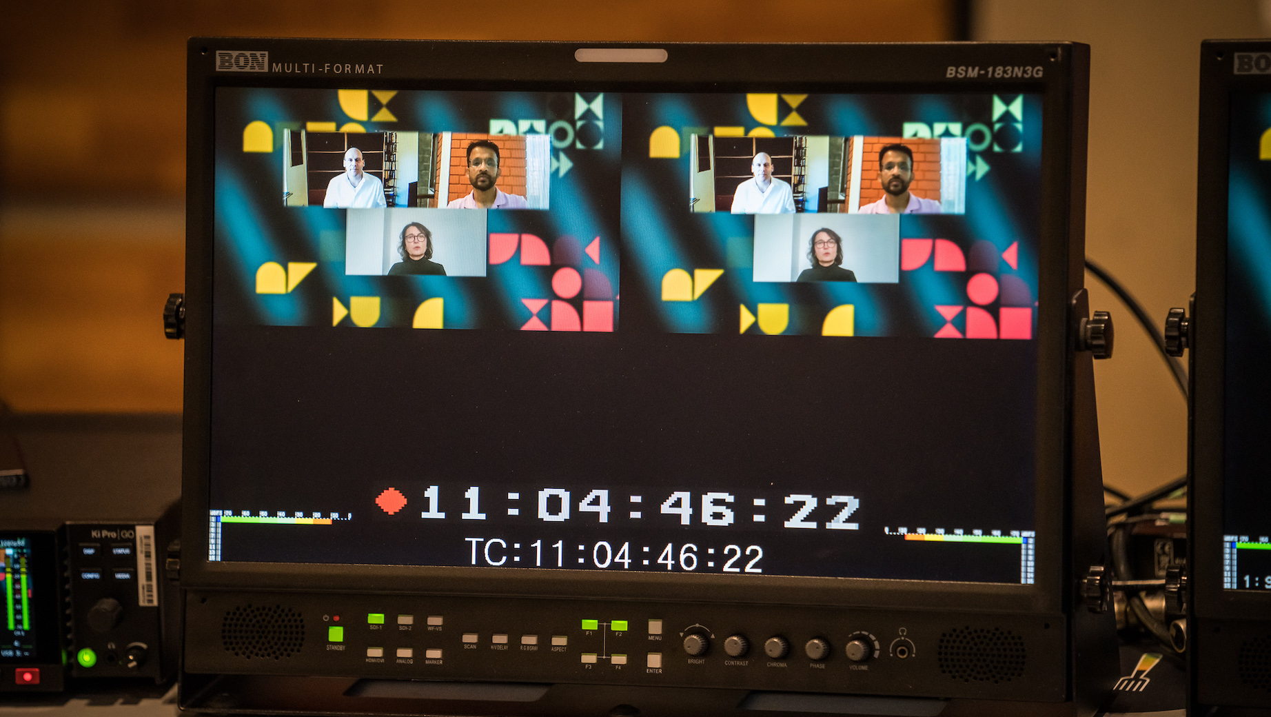 Nahaufnahme eines Kontrollmonitors mit Bildsignal und Timecode-Anzeige. Zu sehen sind zwei Moderatoren und das virtuelle Bühnenbild