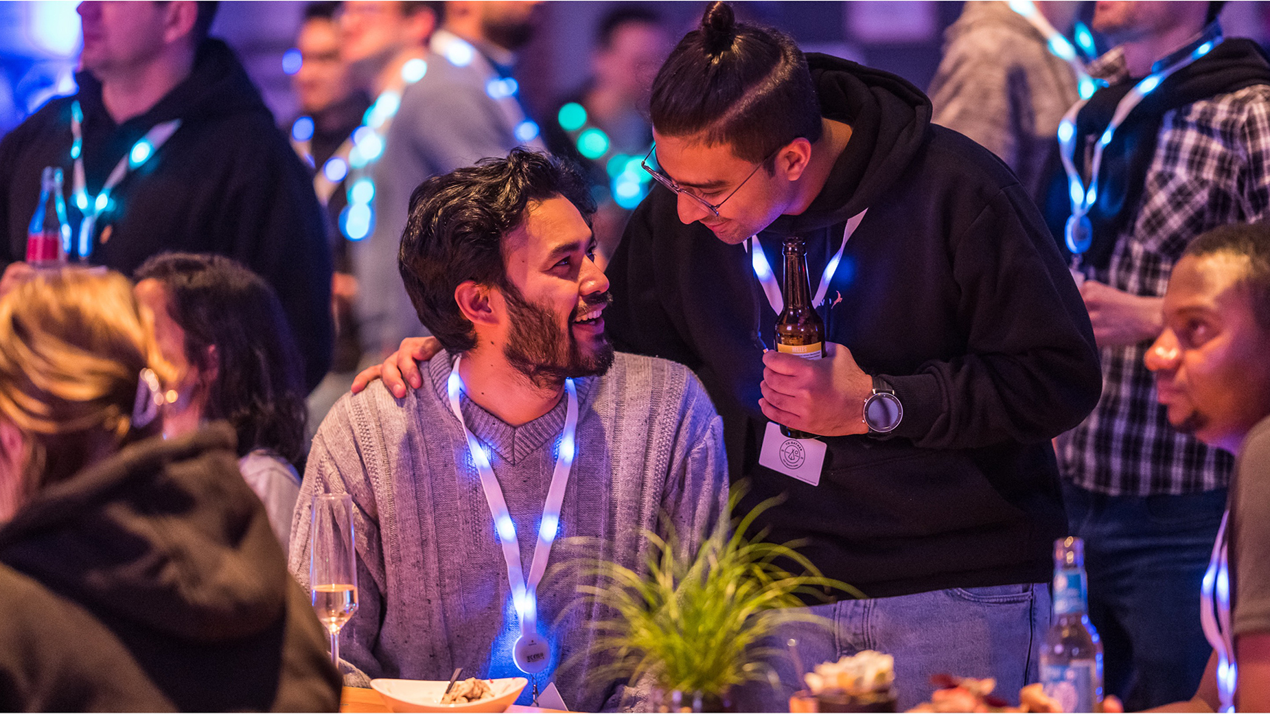 Zwei Männer mit Leuchtbadges mit dem Logo der Veranstaltung