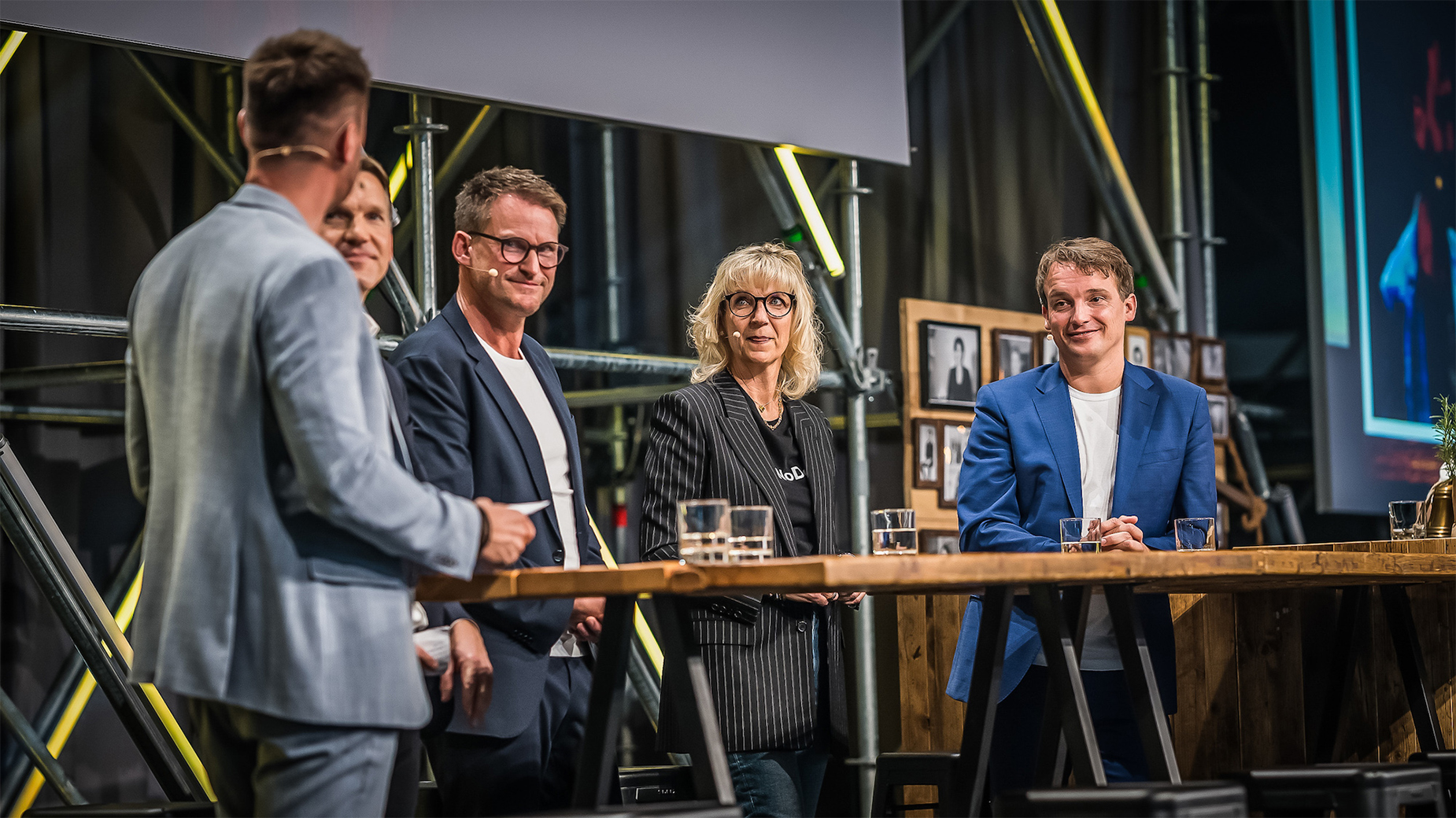 Die Speaker*innen und Moderator*innen der CONNECT, darunter auch Christian Klein, CEO und Mitglied des Vorstands der SAP SE, stehen auf der Hauptbühne an einer Bar und unterhalten sich miteinander.