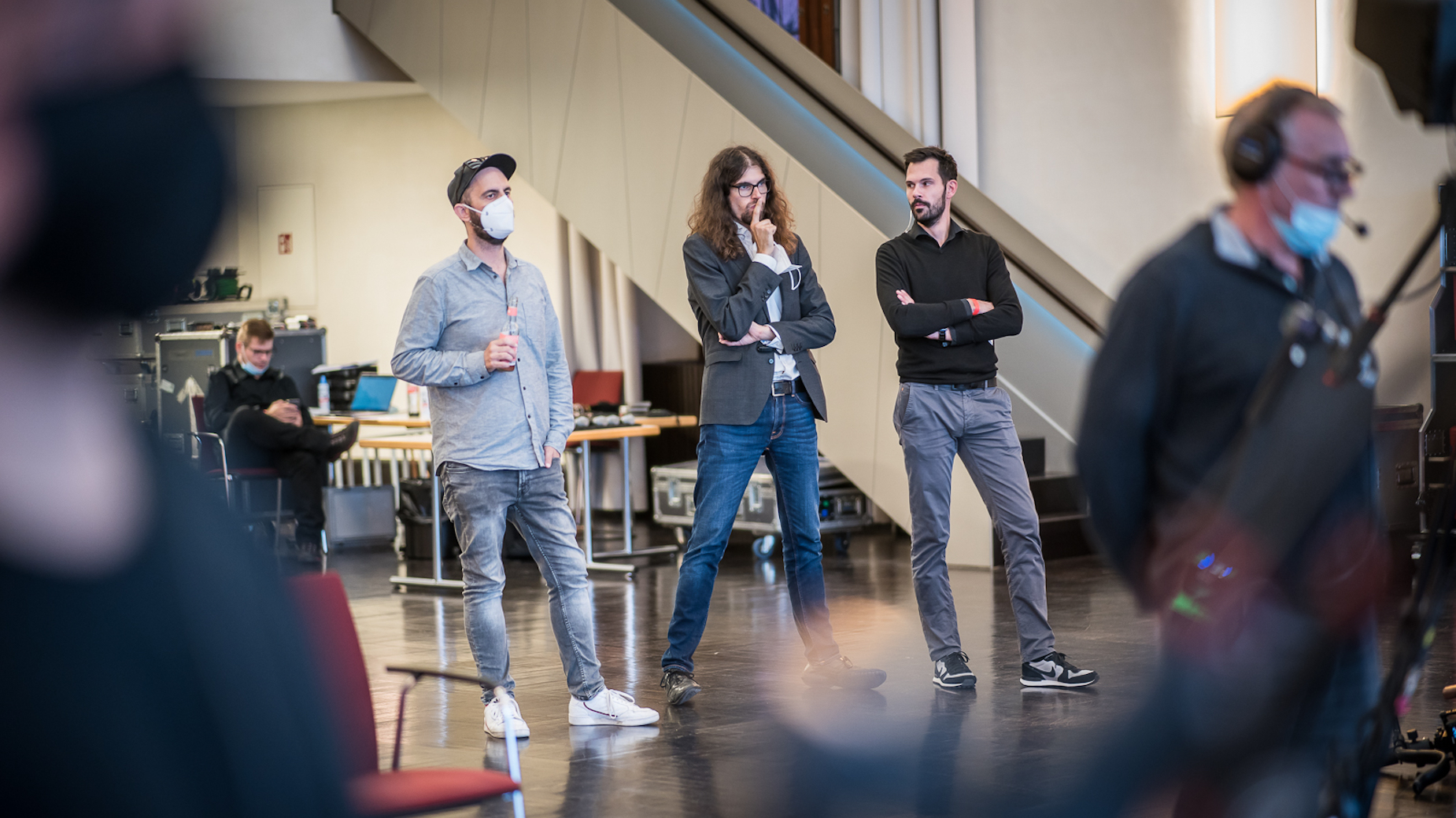 Vier Mitarbeiter von ottomisu stehen in einem Veranstaltungsraum, zwei davon tragen Corona-Schutzmasken. Sie wirken aufmerksam und konzentriert, vermutlich in einer technischen Besprechung oder Generalprobe