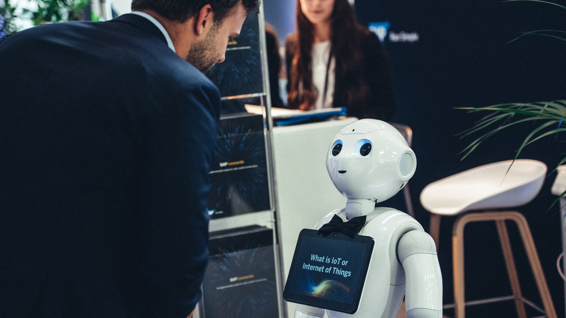 Messebesucher im Gespräch mit humanoidem Roboter mit Display am Körper.