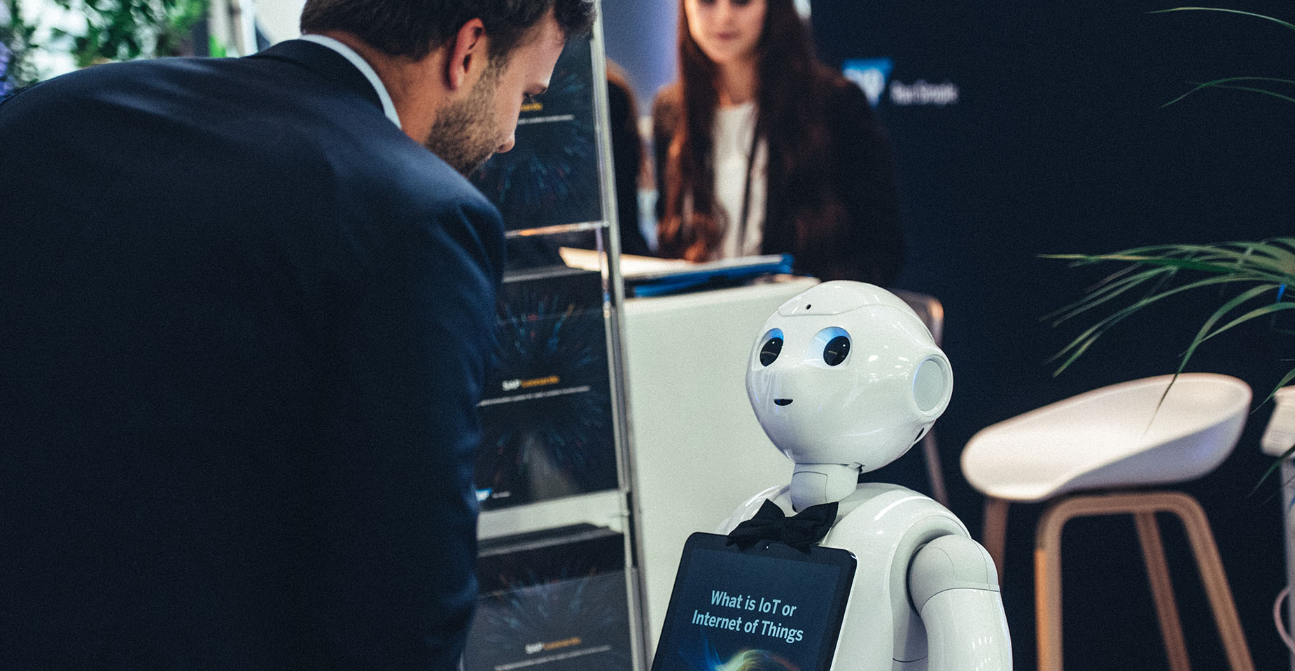 Messebesucher im Gespräch mit humanoidem Roboter mit Display am Körper.
