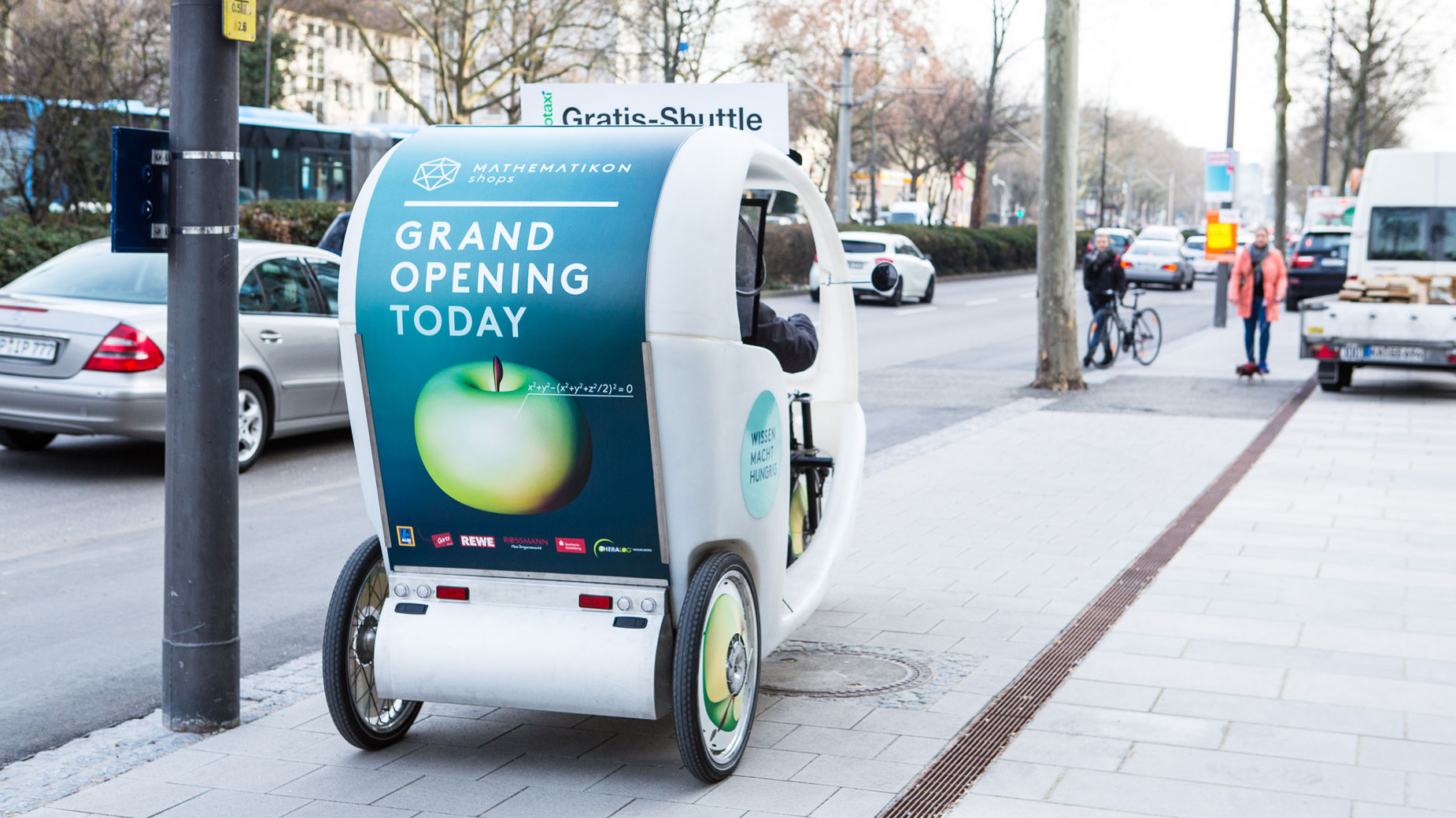 Velotaxi mit Mathematikon-Werbung fährt stadteinwärts auf dem Radweg.