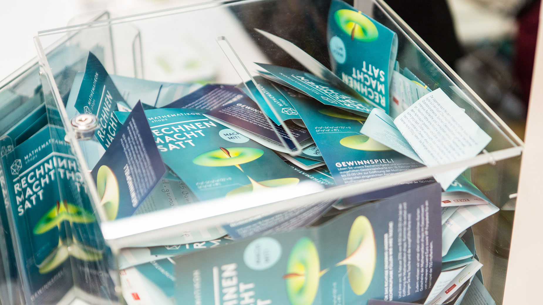 Nahaufnahme gefüllter Gewinnbox mit zahlreichen grünen Teilnahmekarten.