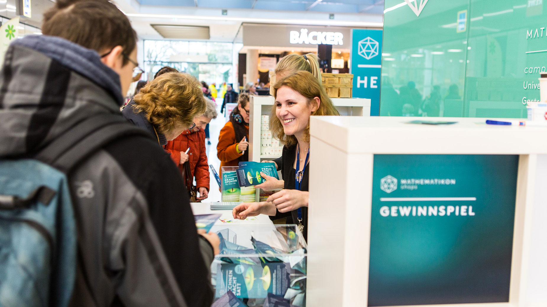 Mitarbeiterin gibt Informationen am Stand mit Mathematikon-Branding.