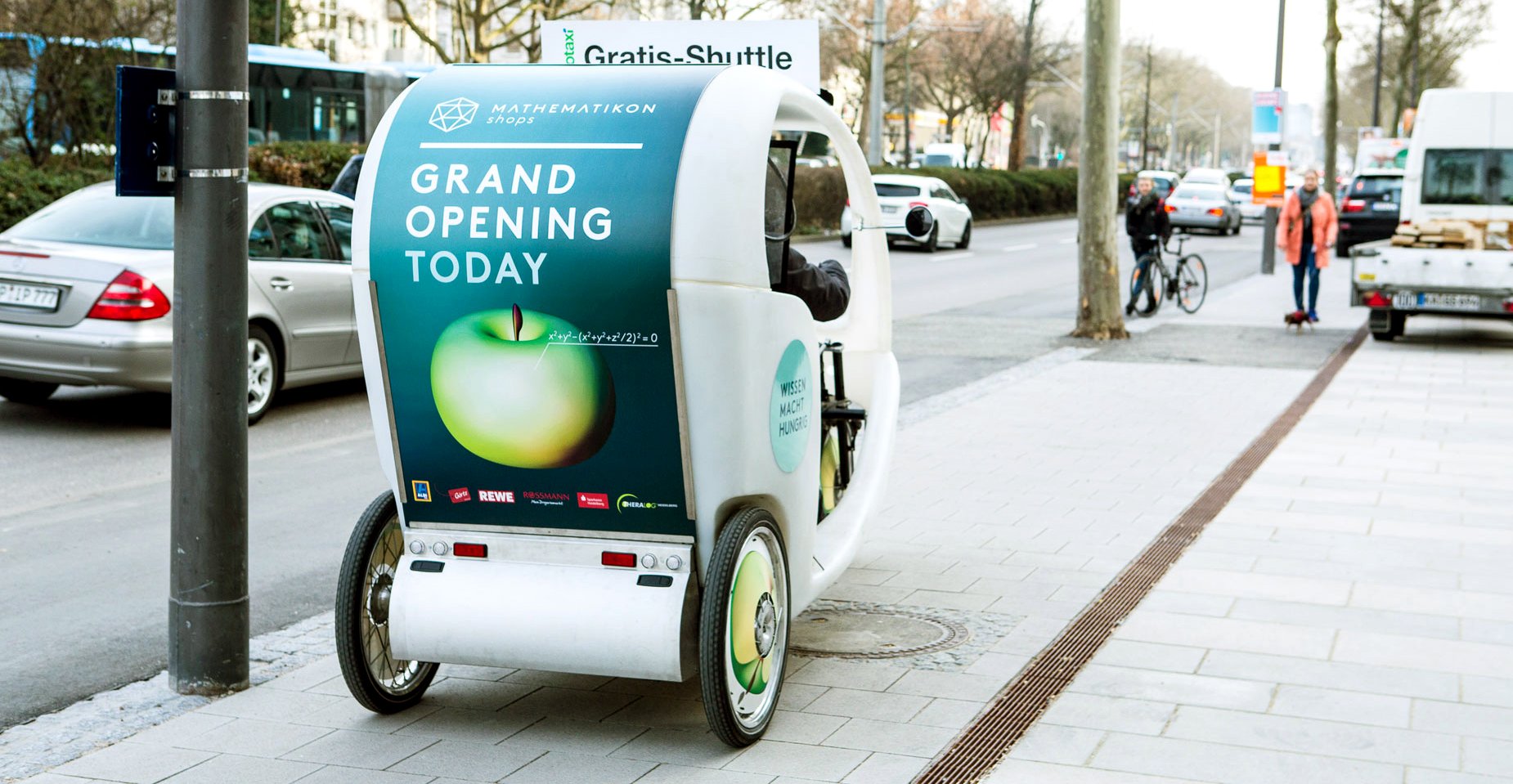 Velotaxi mit Mathematikon-Werbung fährt stadteinwärts auf dem Radweg.