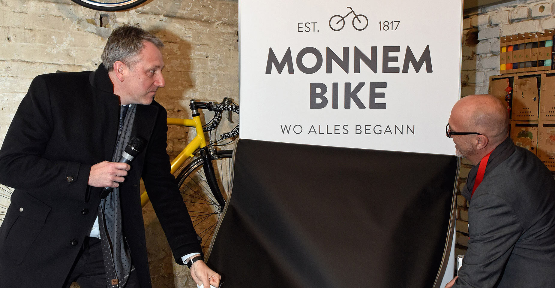 Offizielle Enthüllung des Monnem-Bike-Logos durch zwei Vertreter im historischen Ambiente.