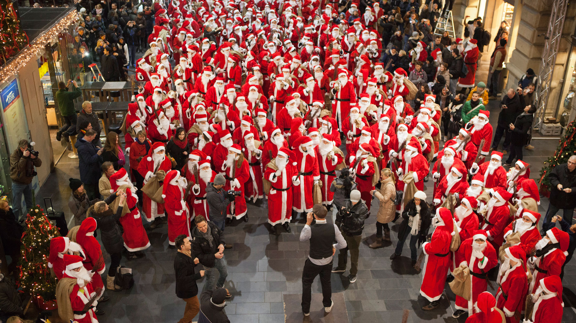 Zahlreiche als Nikolaus verkleidete Menschen singen und tanzen auf dem Bahnsteig des Frankfurter Hauptbahnhofes mit dem Sänger Max Mutzke.