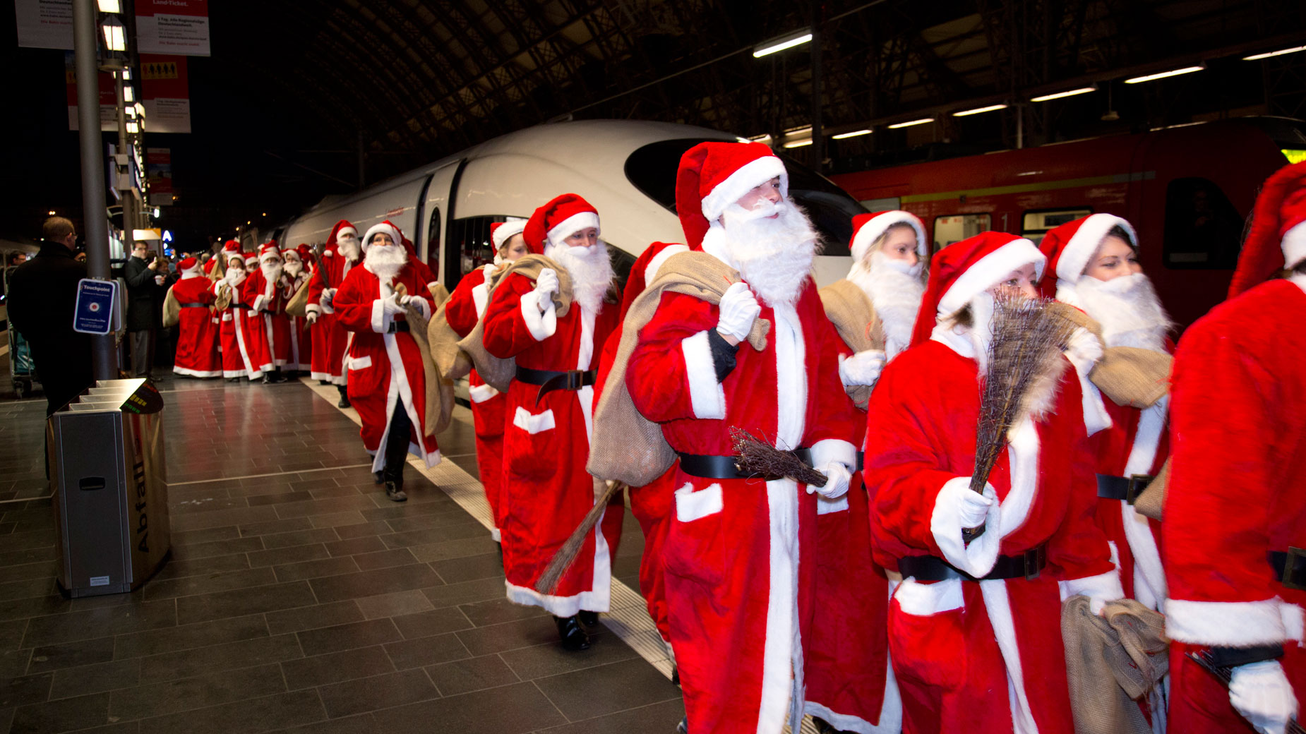 Zahlreiche als Nikolaus verkleidete Menschen laufen auf dem Bahnsteig.