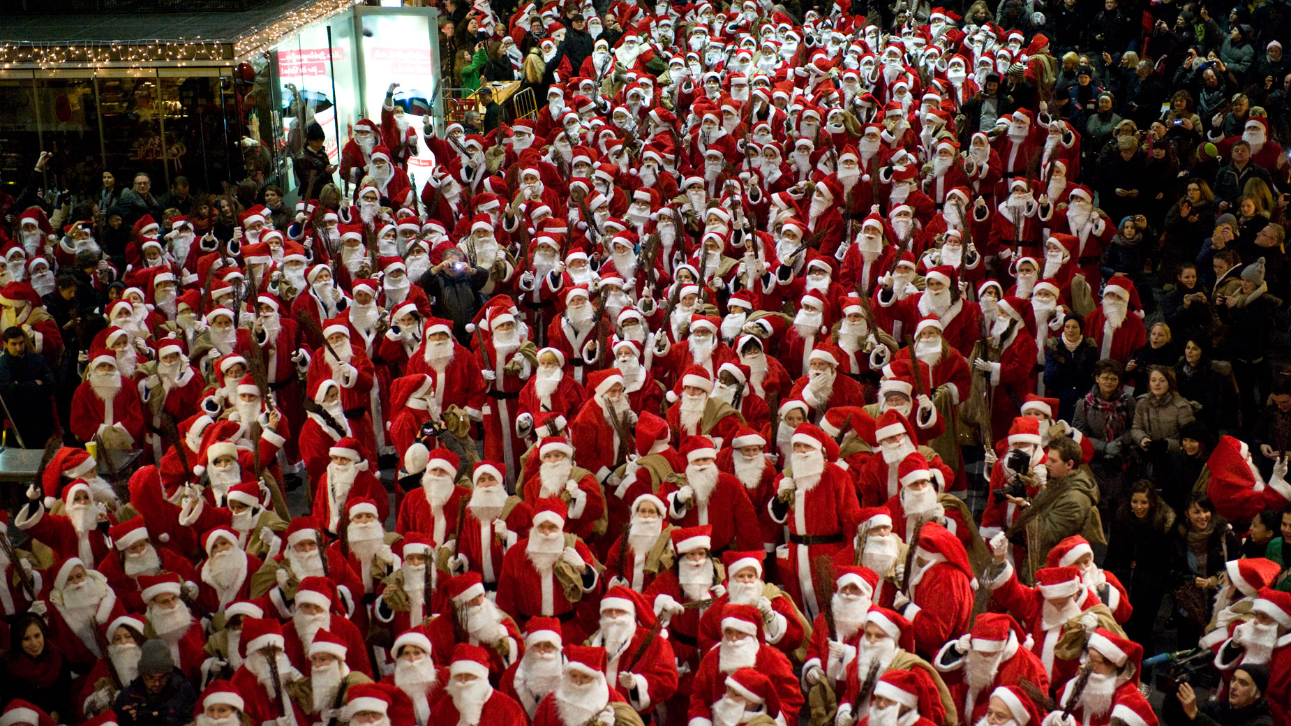 Mehrere verkleidete Nikoläuse mit roten Mützen und weißen Bärten stehen dicht gedrängt zusammen.