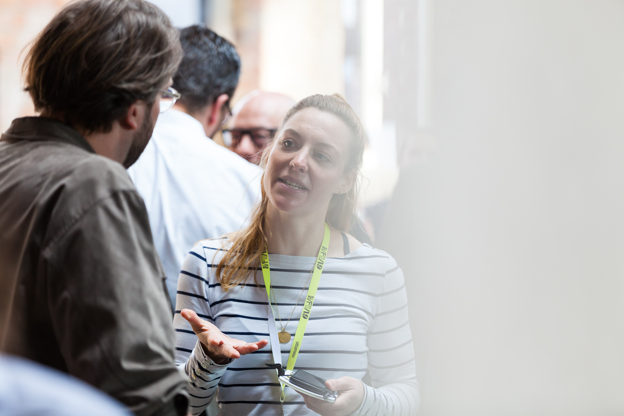Frau lächelt während eines Gesprächs mit einem Mann, beide stehen in einem hellen Veranstaltungsraum.