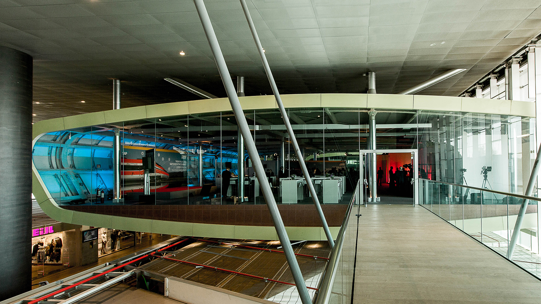 Futuristischer Besprechungsraum mit Glaswänden in einem offenen Gebäudeinterieur.