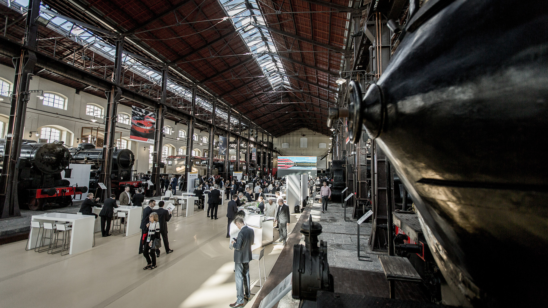 Industriehalle mit alten Lokomotiven und Besuchern zwischen Infopoints und Ausstellungsflächen.