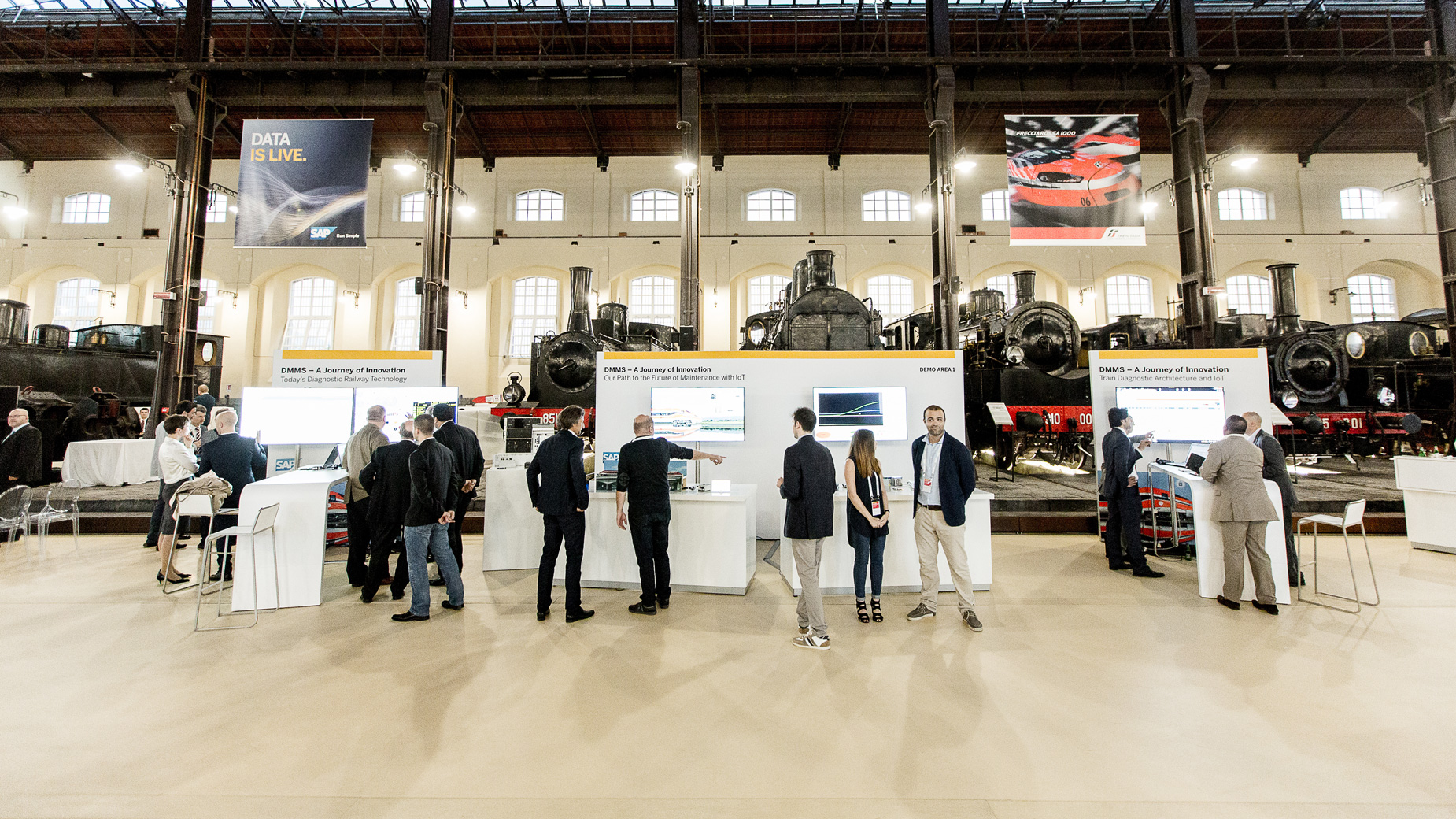 Industriehalle mit alten Lokomotiven und Besuchern zwischen Infopoints und Ausstellungsflächen.