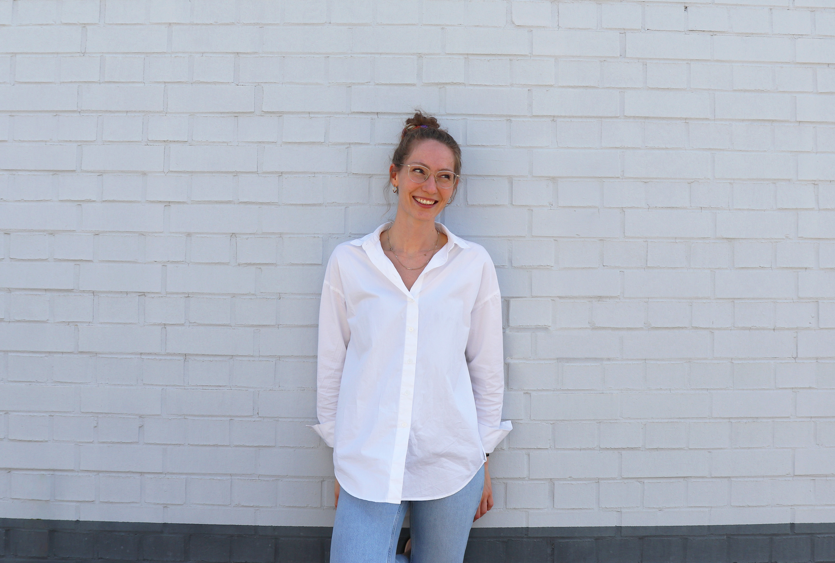 Fotografie von Leonie, die vor einer weißen Hauswand steht