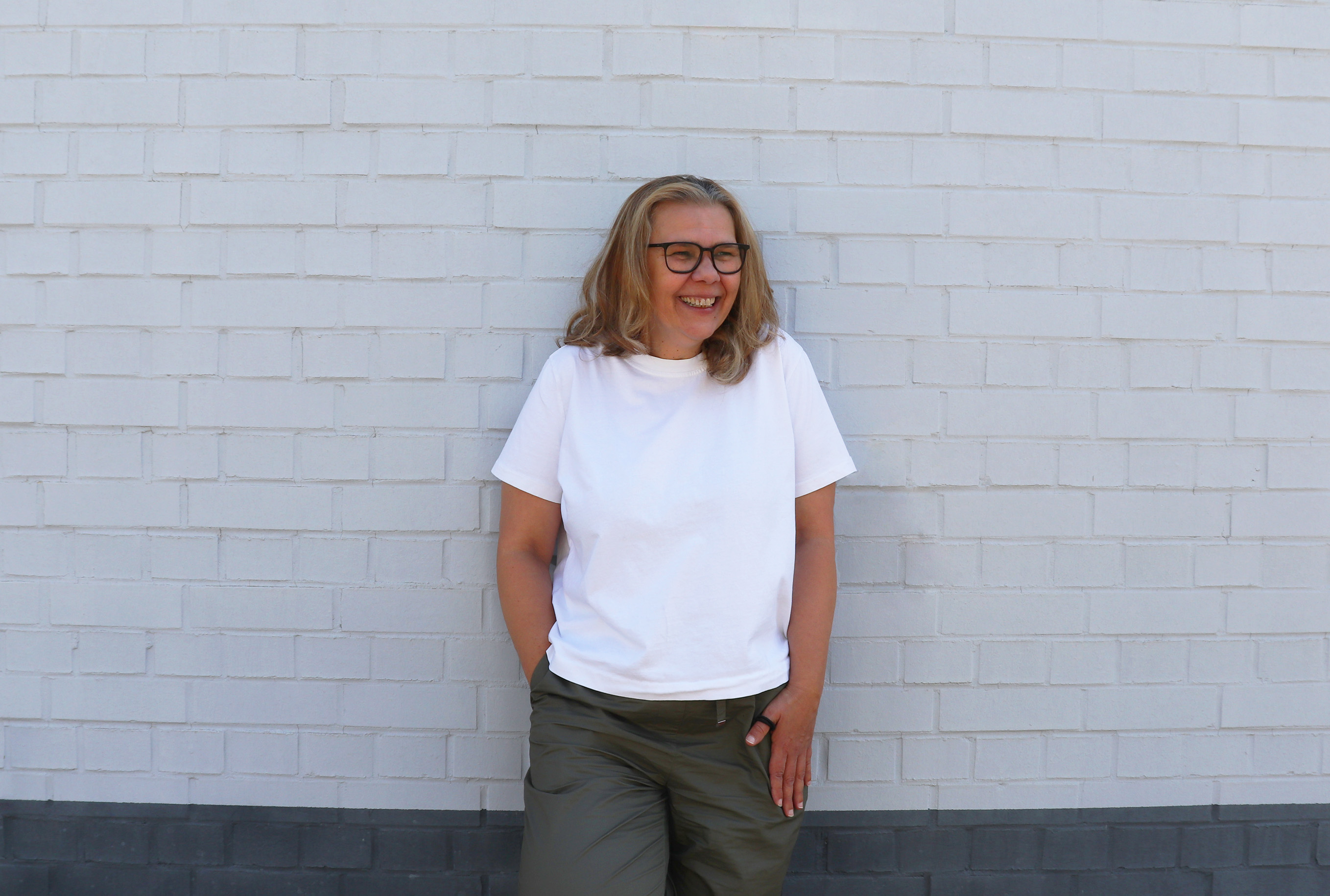 Fotografie von Sanda, die vor einer weißen Hauswand steht