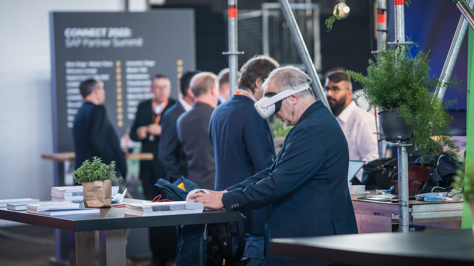 Zu sehen sind mehrere Besucher*innen, eine Person trägt ein Virtual Reality Headset.