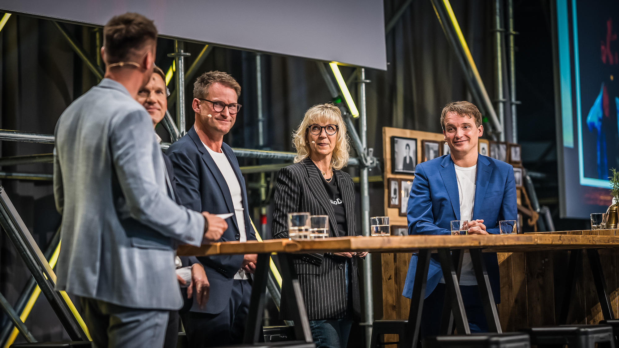 Die Speaker*innen und Moderator*innen der CONNECT, darunter auch Christian Klein, CEO und Mitglied des Vorstands der SAP SE, stehen auf der Hauptbühne an einer Bar und unterhalten sich miteinander.