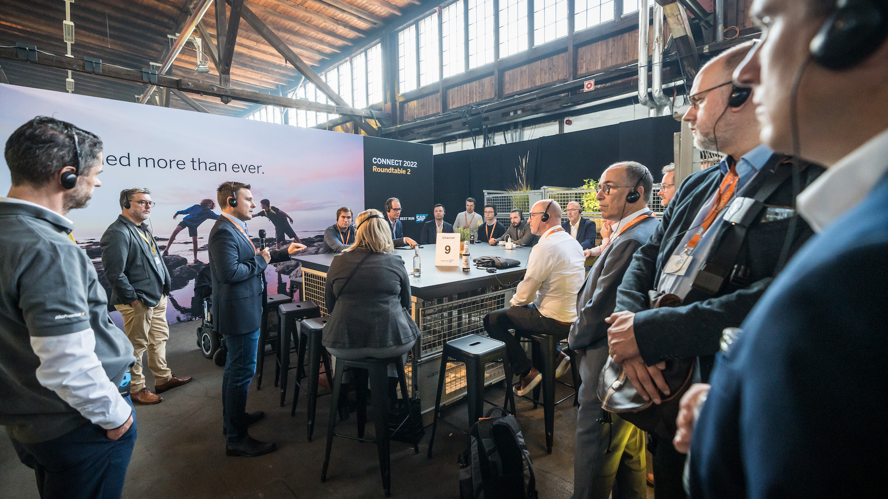 Zu sehen ist ein weiterer Roundtable mit vielen Besucher*innen, die Kopfhörer tragen.