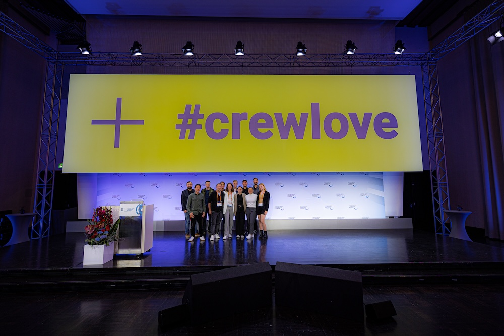 Teambild auf der Bühne mit dem Schriftzug #crewlove auf gelbem Hintergrund