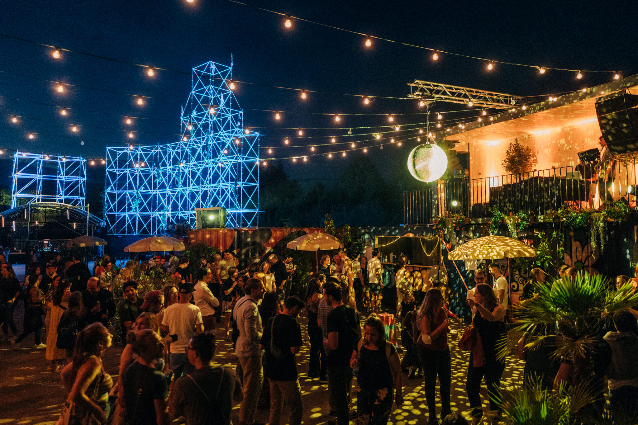 Outdoor Veranstaltung mit leuchtenden Gerüsten und einer großen Discokugel