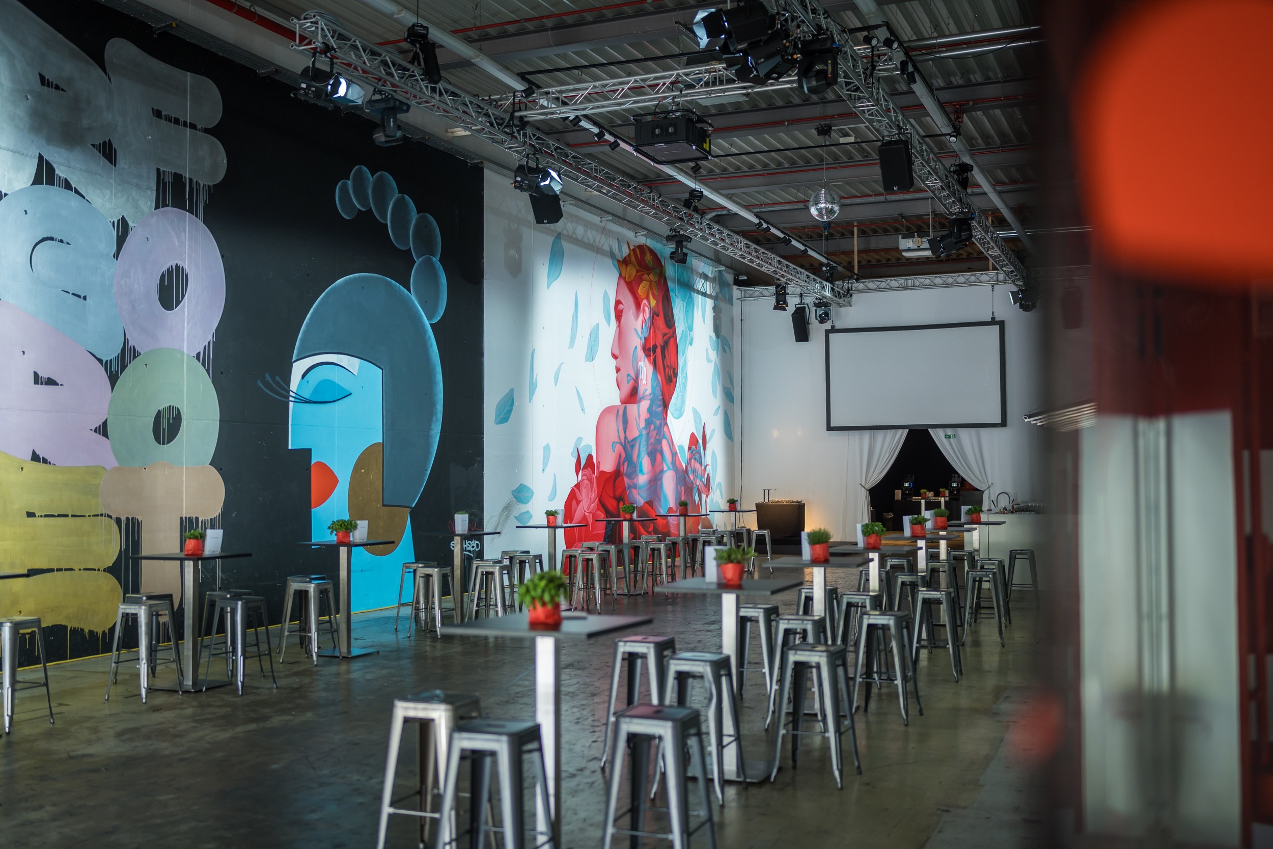 Stehtische vor großen Wandgemälden